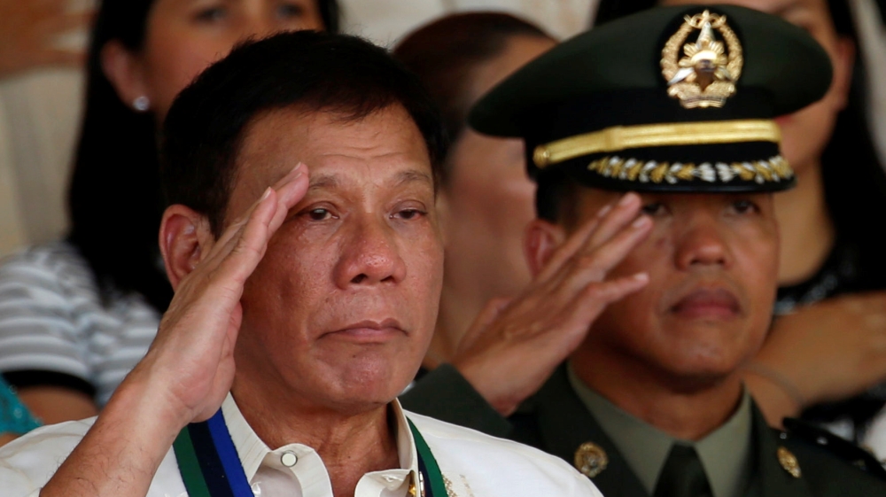 Philippines President Rodrigo Duterte salutes next to a military officer at main military Camp Aguinaldo in Quezon city Metro Manila