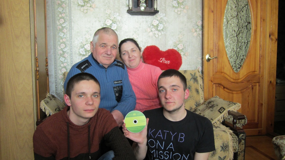   Lyudmila Kaminska with her father and sons Sergei, left, and Andrei, right, display a warning video they received from a collection agency, at their home in Vinnytsia [Chris Scott/Al Jazeera]  