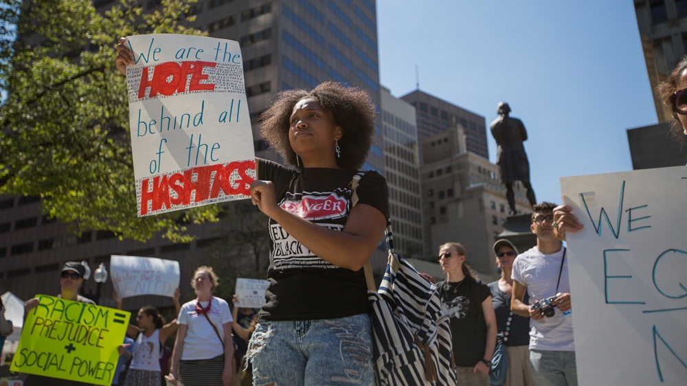 Shalece Perryman-Welch holds up a sign that reads, 'We are the hope behind all of the hashtags,' outside Faneuil Hall   [Carolyn Bick/Al Jazeera]  