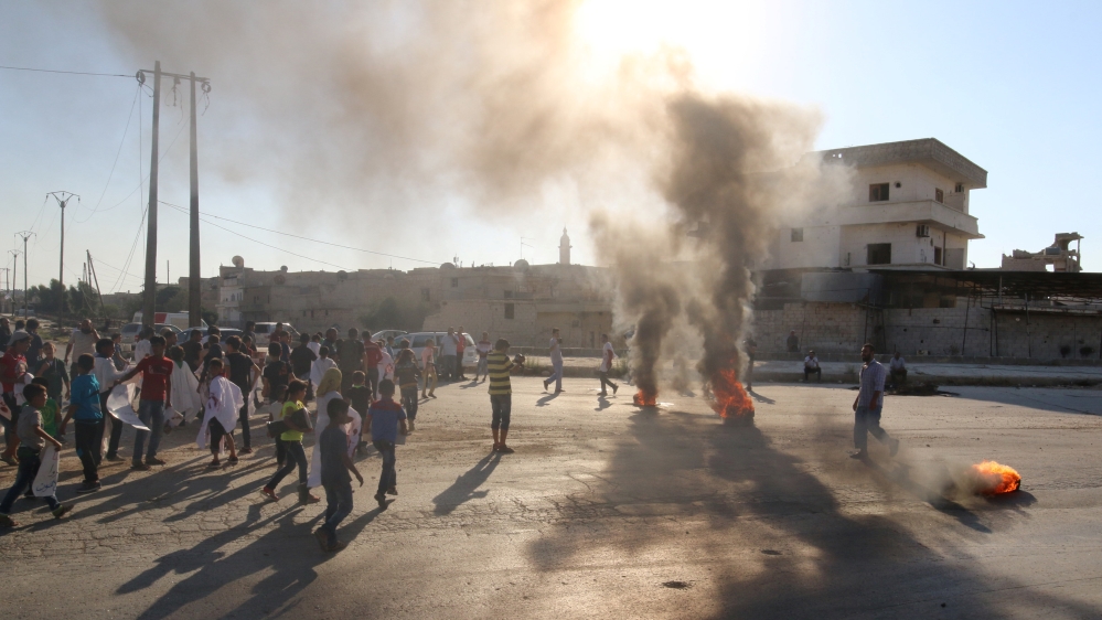 People gather near burning tyres during a demonstration against forces loyal to Assad and calling for aid to reach Aleppo near Castello road in Aleppo, Syria [REUTERS]