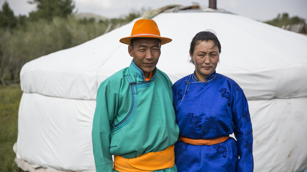 One of the collective PUG community managers stands for a portrait with his wife in Ikh Tamir [Taylor Weidman/Al Jazeera]