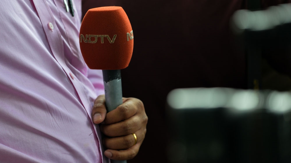 A news reporter with the Indian news channel NDTV holds a microphone.