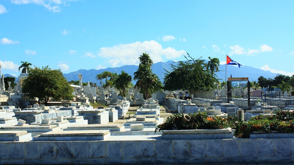 The only things that separate the cemetery from the poor neighbourhood of Aguero behind it are a wall and a dusty embankment  [Al Jazeera] 