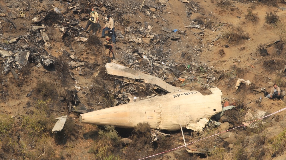 Rescue workers survey the site of a plane crash in the vilage of Saddha Batolni near Abbotabad