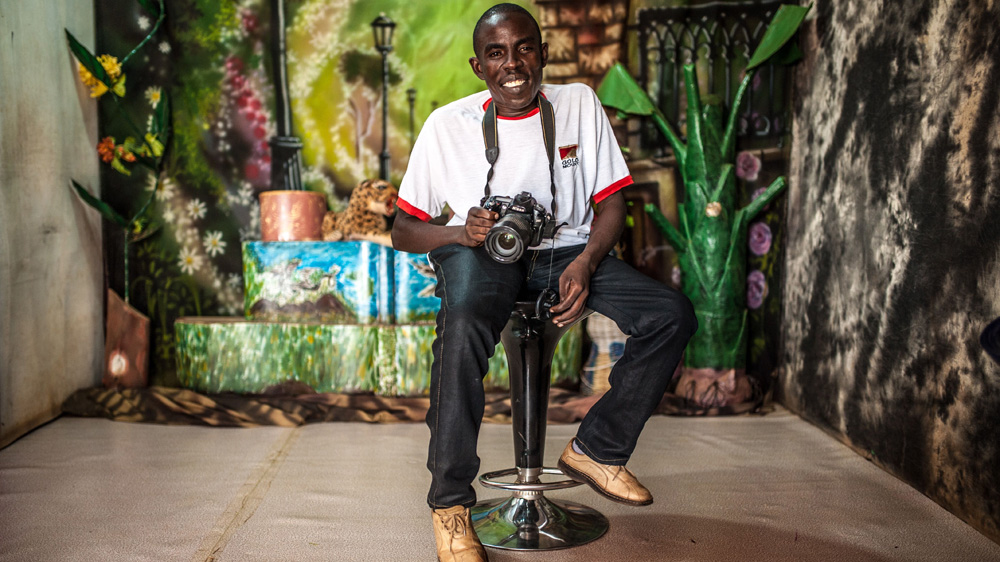 Chairman of the Youth for Disability Association and a beneficiary of the Connecting the Dots programme, Hassan Rajib, 29, sits in his photo studio in Kiryandongo, Uganda [Aurelie Marrier d'Unienville/Sightsavers/Al Jazeera]