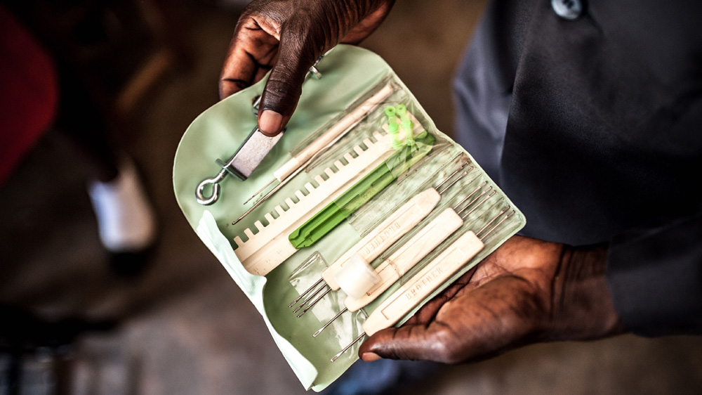 Simon Peter Otoyo's holds knitting tools for his students at Amor Foundation Vocational Training, Bweyale, Uganda [Aurelie Marrier d'Unienville/Sightsavers/Al Jazeera]