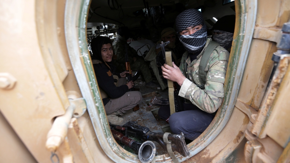 Rebel fighters ride a military vehicle, as they advance towards the northern Syrian town of al-Bab
