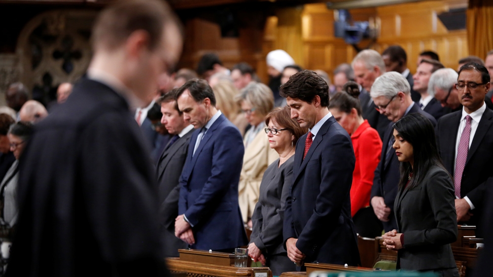 Trudeau, right, joins MPs in a moment of silence in the House of Commons [Reuters]