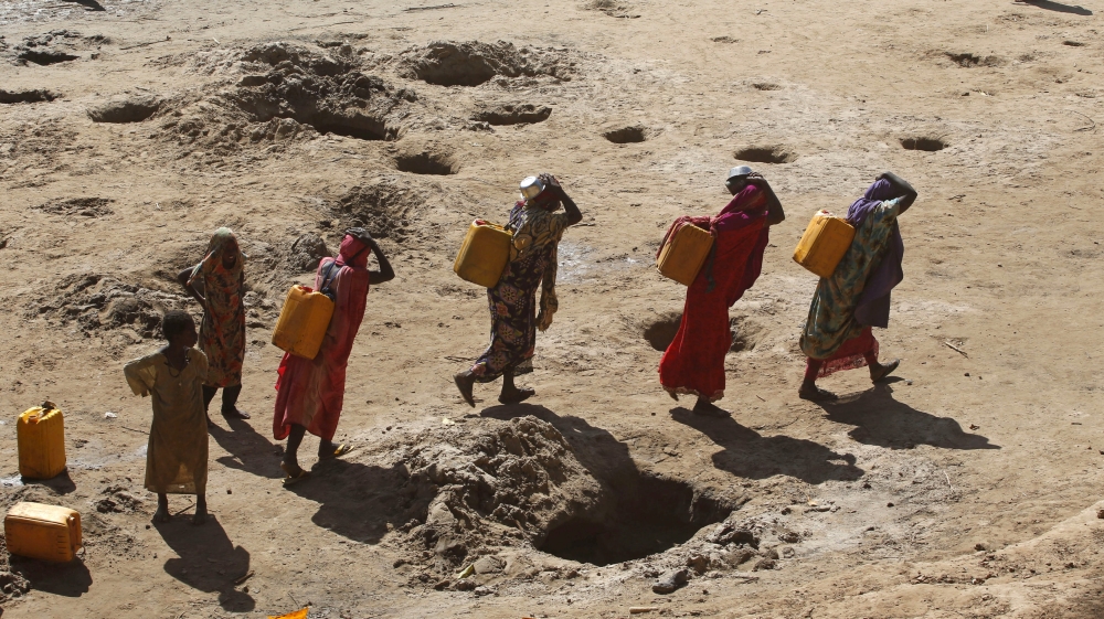 Women carry jerry cans of water from shallow wells dug from the sand along the Shabelle River bed, which is dry due to drought in Somalia''s Shabelle region