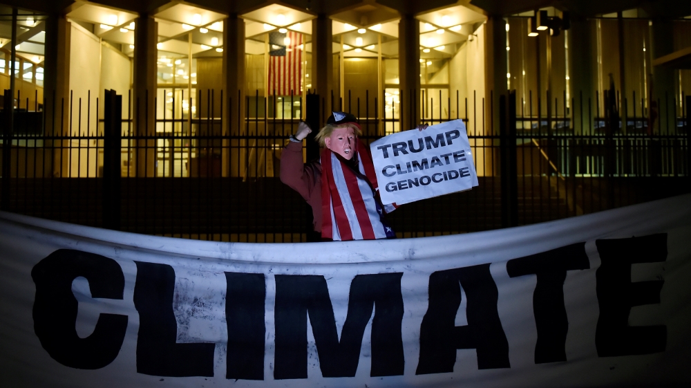 A man wearing a mask depicting U.S. President-Elect Donald Trump protests during a demonstration against climate change outside of the U.S. Embassy in London
