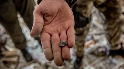 A police officer shows the piece of shrapnel in destroyed house. 'From my experience, it looks like the element of 122mm shell,' he says  [Anton Skyba/Al Jazeera]