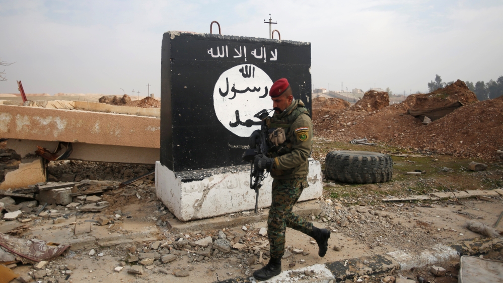 An Iraqi soldier walks next to a wall painted with the black flag commonly used by Islamic State militants, during a battle with Islamic State militants near Arabi neighborhood, north of Mosul
