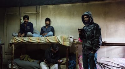 Pakistani migrant workers sit in their home, constructed partly from a metal cargo container [Will Horner/Al Jazeera]