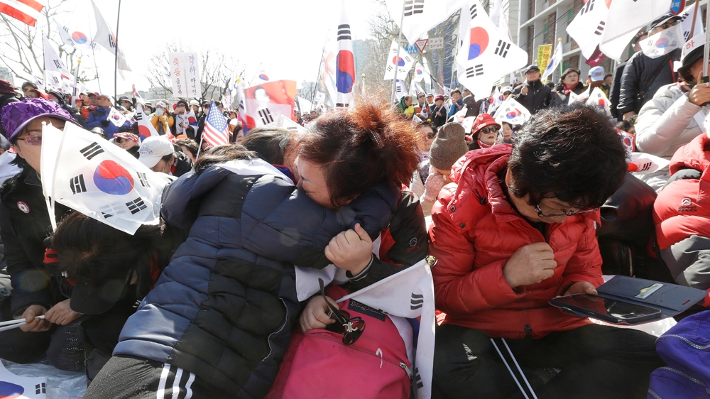 Supporters of South Korean President Park Geun-hye weep during a rally opposing her ouster on Friday [AP]