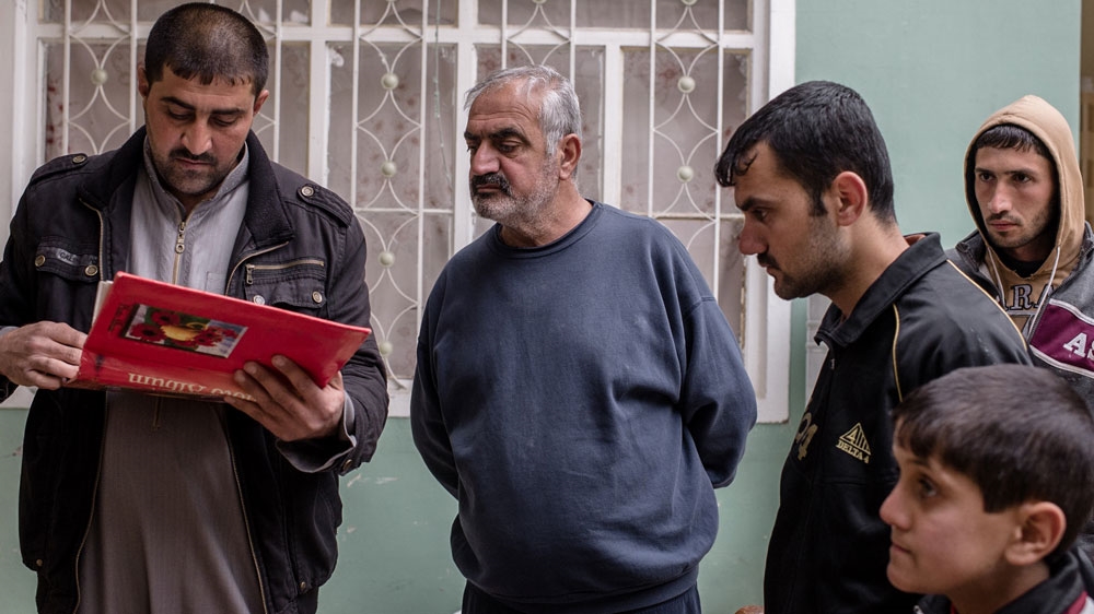 Neighbors looks through a family photo album recovered from the rubble after the airstrike in the "New Mosul" neighborhood of west Mosul on March 17, 2017.