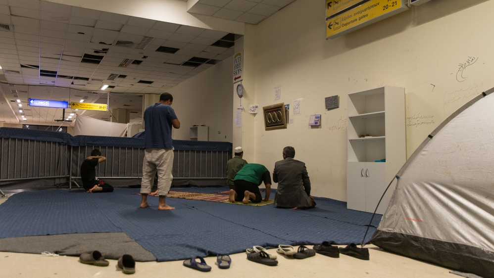 Afghans pray inside the abandoned airport hangar at the Elliniko camp [Kelly Lynn Lunde/Al Jazeera]
