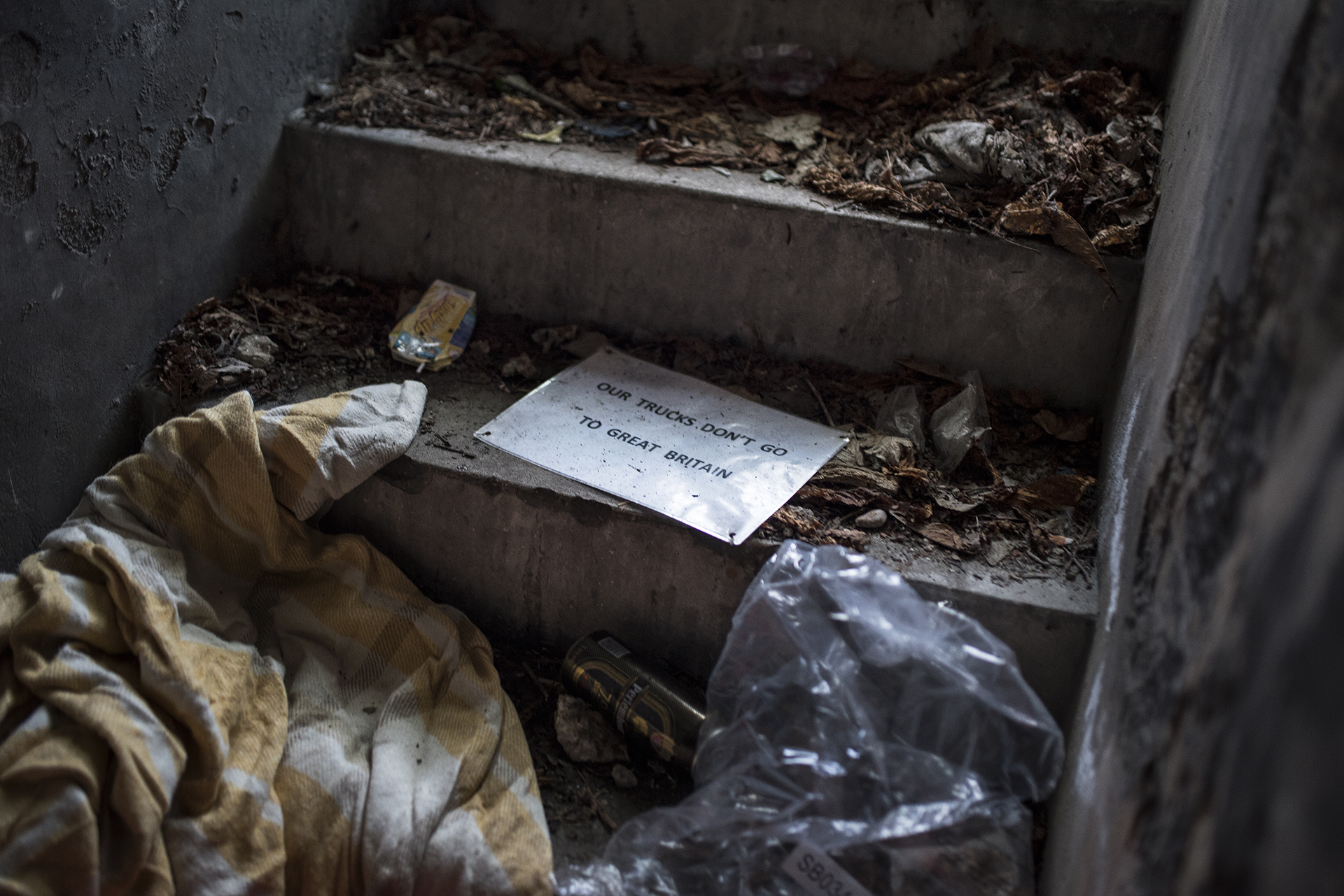 A sign pulled off a truck lies inside a bunker where refugees are living in Calais after the 'Jungle' was closed down [Guillem Trius/Al Jazeera]