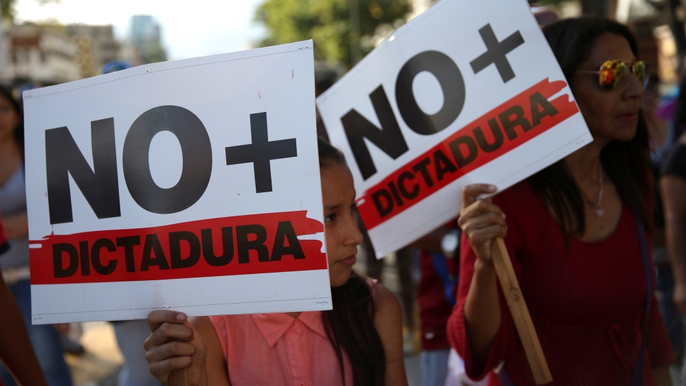 Opposition supporters holding a placards that read "No more dictatorship", take part in a protest against Venezuelan President Nicolas Maduro''s government in Caracas