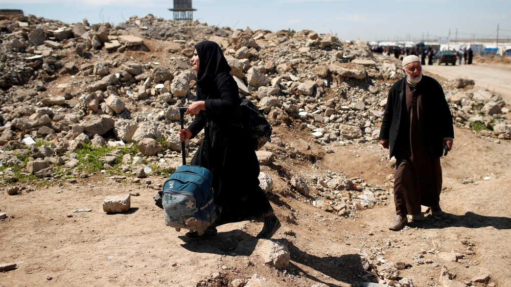Displaced Iraqis who had fled their homes pass a destroyed building outside Hammam al-Alil camp south of Mosul