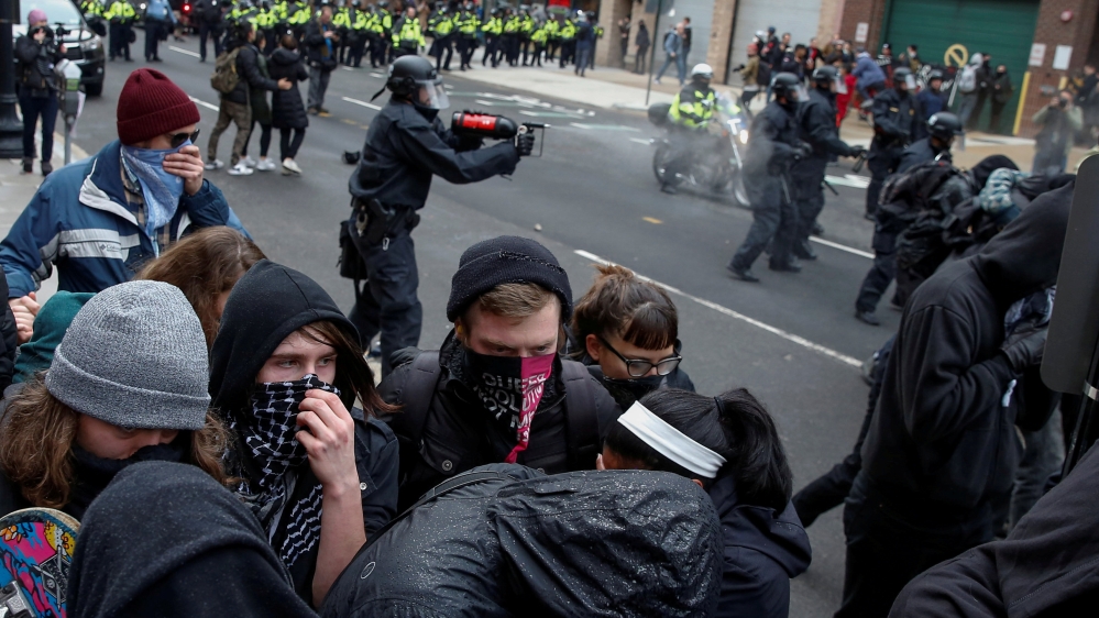Protesters against Trump's inauguration take cover as they are hit by pepper spray by police [Adrees Latif/Reuters]