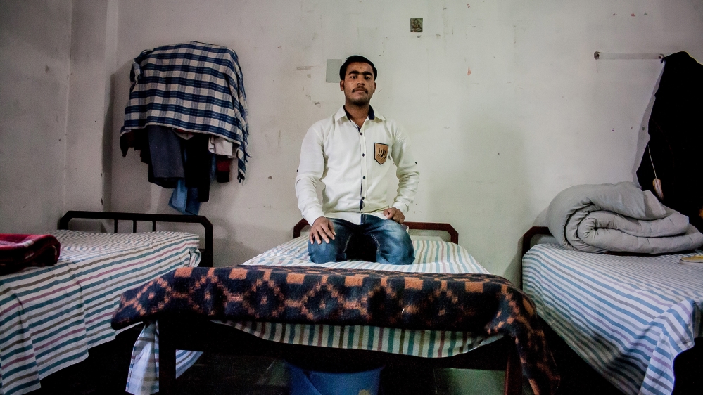 Yogi sits on his bed in his hostel room that he shares with two roommates at Swami Harsewanand Public School. [Radhika Iyengar/Al Jazeera]