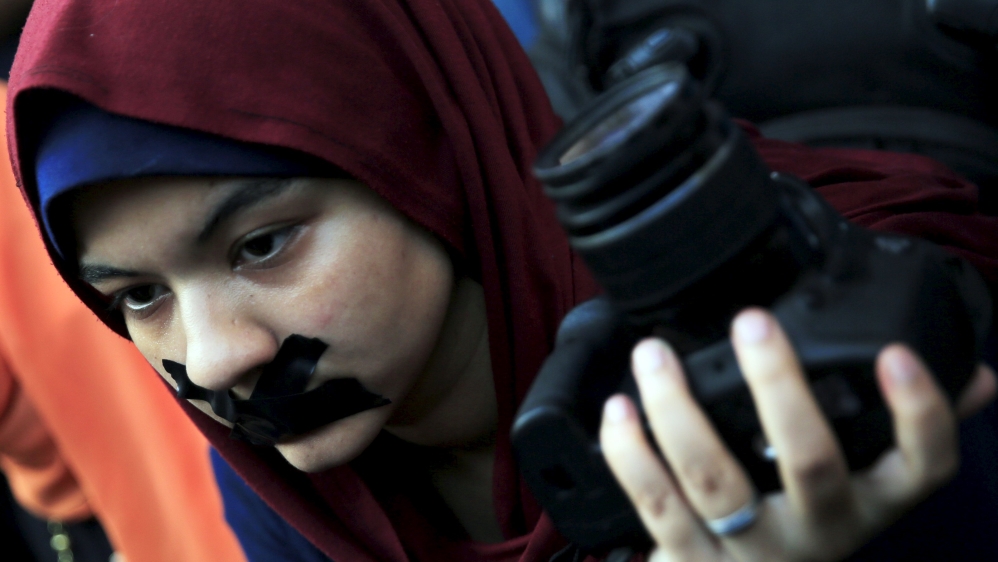 A news photographer with her mouth tapped and holds up her camera during a protest against the detention of Ahmed Ramadan, a photojournalist with Egyptian private newspaper "Tahrir", in Cairo
