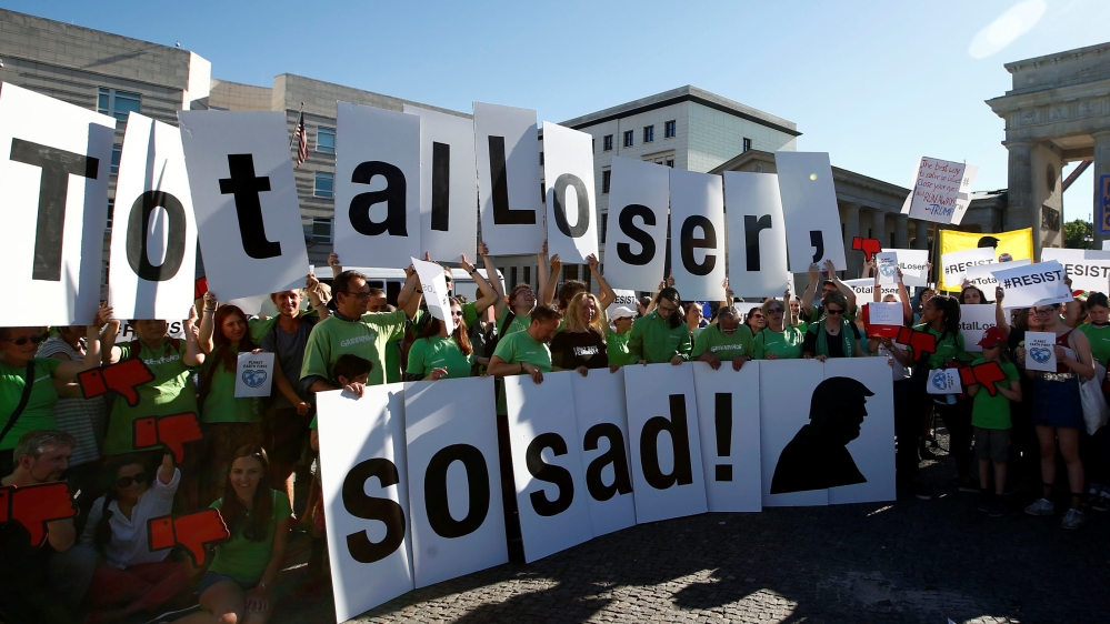 People hold banners as they protest next to the Brandenburg Gate, beside the U.S. embassy, against the U.S. withdrawal from the Paris climate change deal, in Berlin