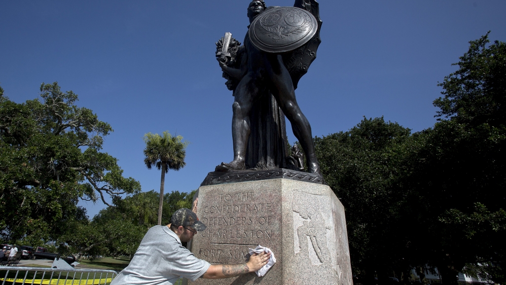 Mullins cleans graffiti off the pedestal of a bronze statue to the "Confederate defenders of Charleston" in Charleston