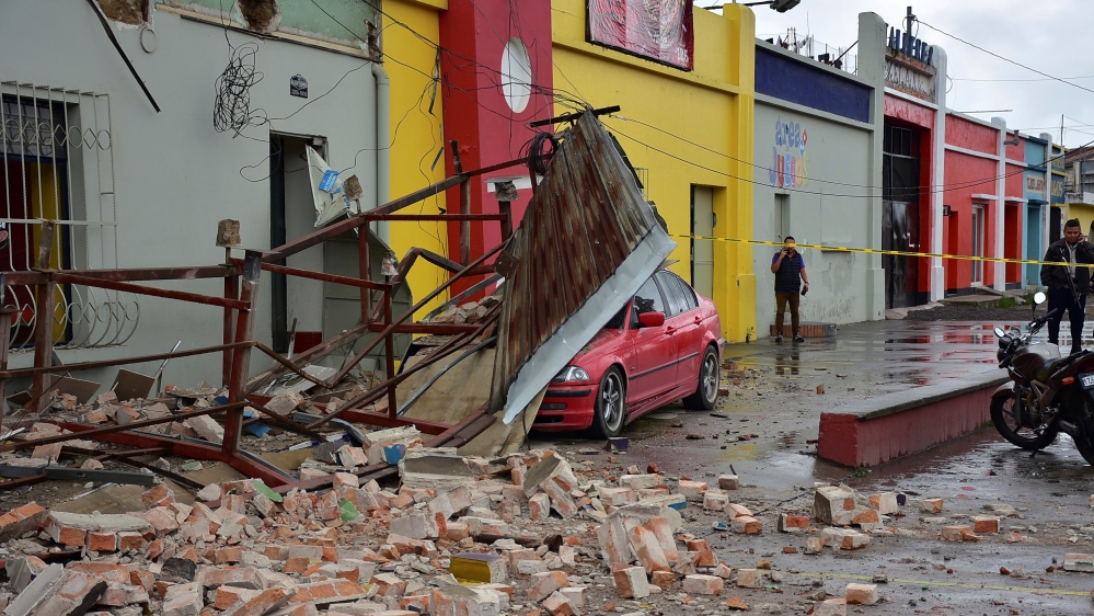 Car covered by debris is seen near a collapsed billboard following an earthquake in Quetzaltenango