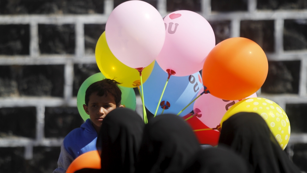 Women look at a boy selling balloons during a gathering marking the birth anniversary of the Prophet Mohammed in Yemen''s capital Sanaa