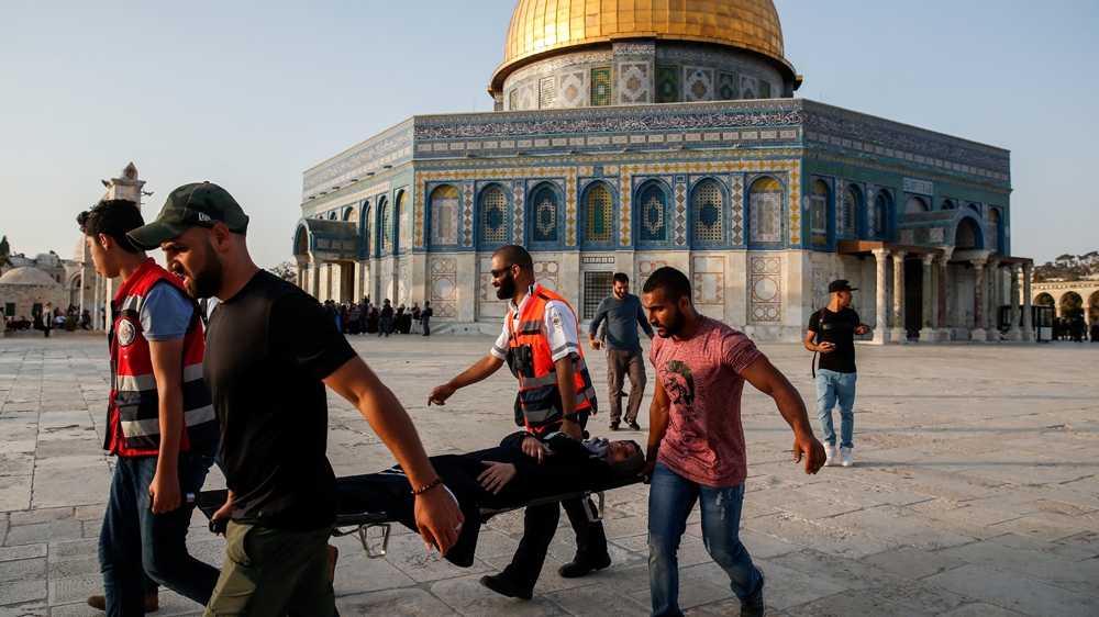 Palestinian paramedics carry an injured woman on a stretcher after clashes [Ahamd Gharabli/AFP]