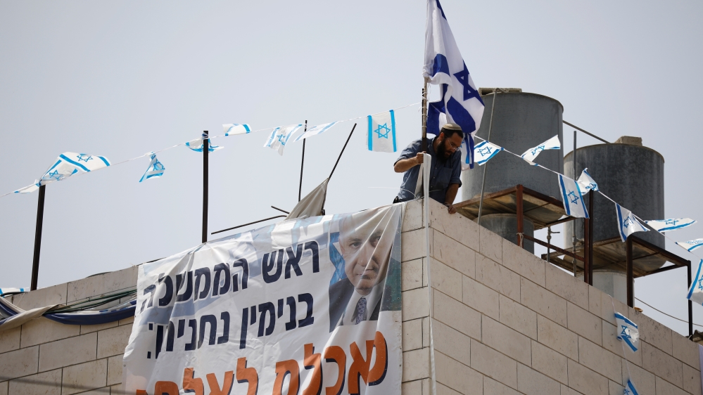 A Jewish settler adjusts a banner to a disputed building where about a hundred hard-line Jewish settlers have hunkered down, in the West Bank city of Hebron