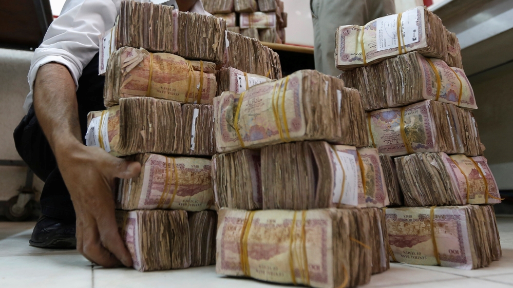 Man carries piles of Yemeni currency.