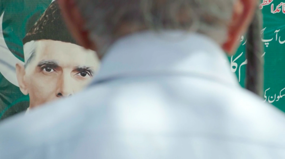 Mr Khanna in front of a poster that depicts Muhammad Ali Jinnah, the founder of Pakistan [Al Jazeera]