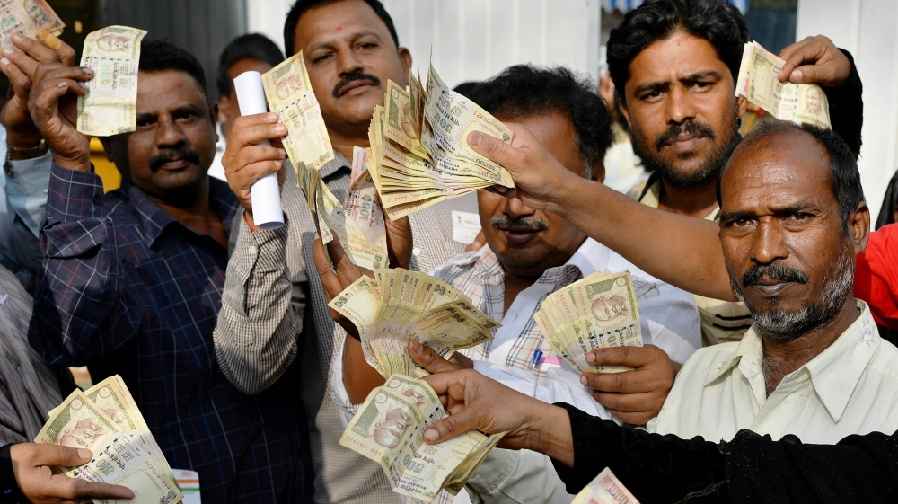 People waiting to exchange demonitised Indian currency, show their old 500 and 1,000 rupee notes near the closed gates of Reserve Bank of India on January 2, 2017