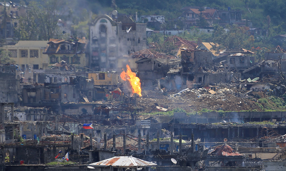 Flame rises as damaged buildings are seen after government troops cleared the area from pro-Islamic State militant groups inside a war-torn area in Marawi city, southern Philippines October 23, 2017.