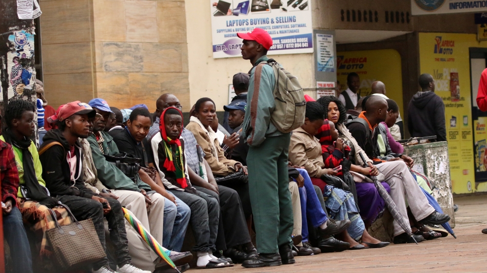 People queue to draw money outside a bank in Harare