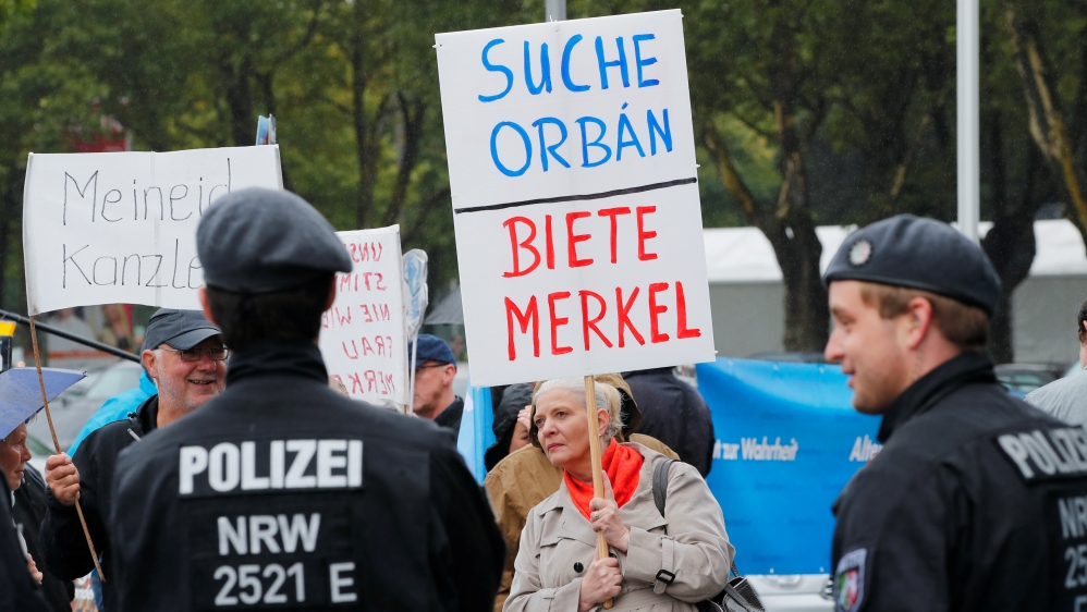 Members of Germany's Alternative for Germany (AFD) party protest in Dortmund against then-Chancellor Angela Merkel, in the run-up to the country's general election, on August 12, 2017. The placard reads, 