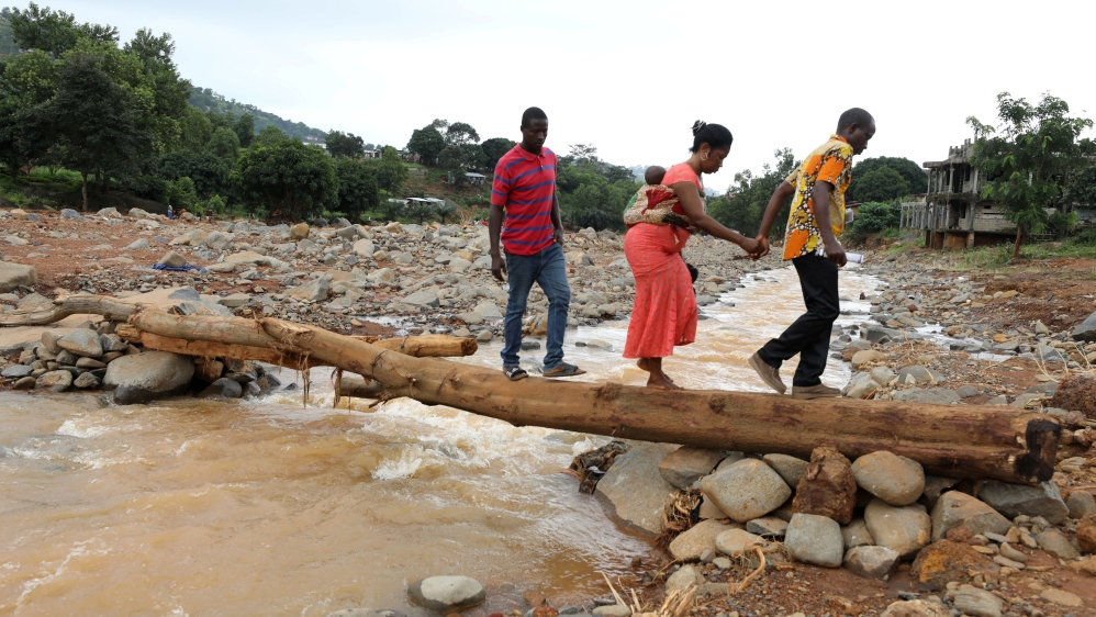 A man helps a woman cross a log bridge after the flash flood washed away a concrete bridge at Pentagon, in Freetown August 18, 2017. REUTERS/Afolabi Sotunde TPX IMAGES OF THE DAY