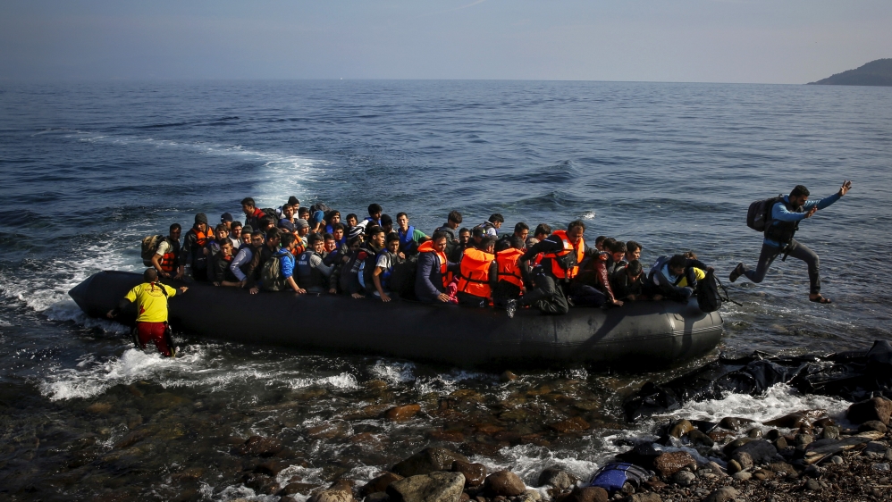 An Afghan migrant jumps off an overcrowded raft onto a beach in the Greek island of Lesbos