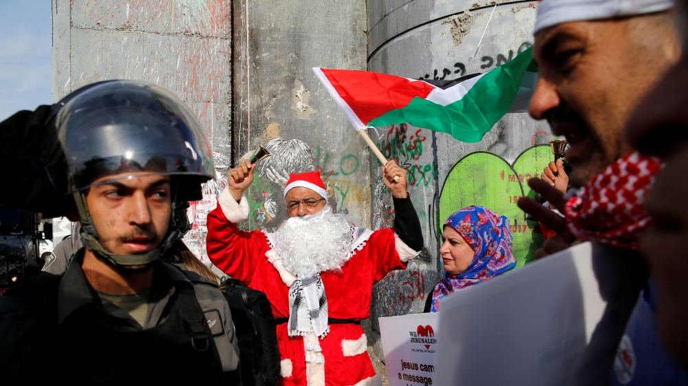 Palestinian dressed as Santa Claus stands next to an Israeli border police during clashes in the West Bank city of Bethlehem