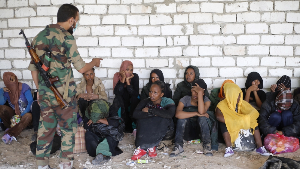 A Libyan soldier talks to African migrants after they were detained in Zawiya northern Libya