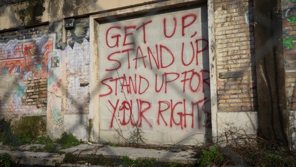 Graffiti spray-painted on an abandoned building near Baobab Experience urges refugees to fight for their rights [Patrick Strickland/Al Jazeera] 