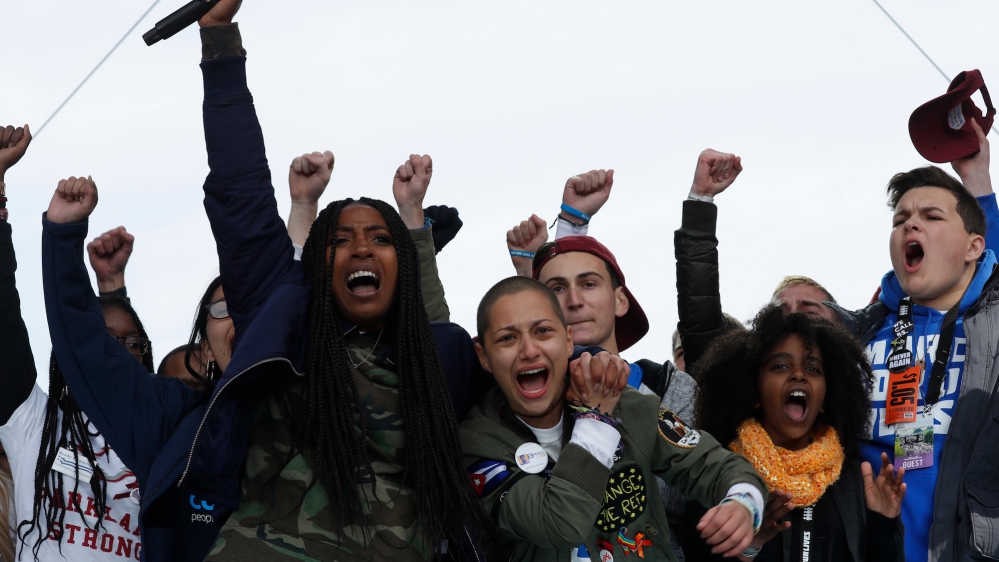 Shooting survivors Tyra Hemans, centre-left, and Emma Gonzalez, centre-right, from Marjory Stoneman Douglas High School in Parkland, Florida, hug as Hemans addresses the conclusion of the 'March for Our Lives' event demanding gun control [Jonathan Ernst/Reuters]