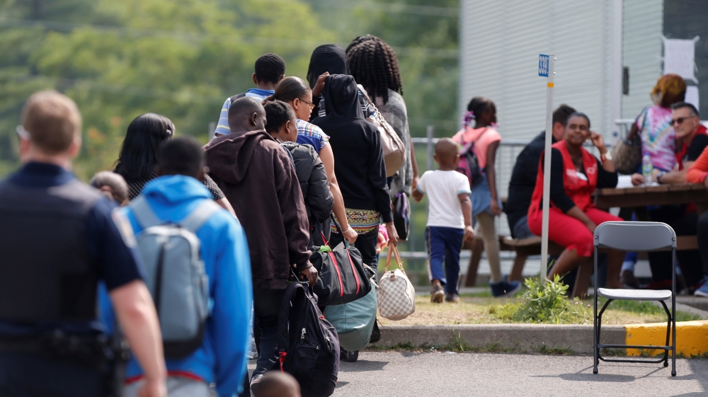 FILE PHOTO: A group of asylum seekers wait to be processed after being escorted from their tent encampment to the Canada Border Services in Lacolle