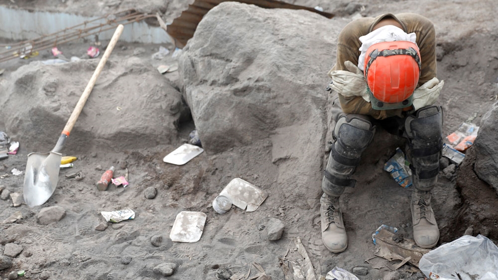 A rescue worker rests in an area affected by the eruption of the Fuego volcano [Carlos Jasso/Reuters] 