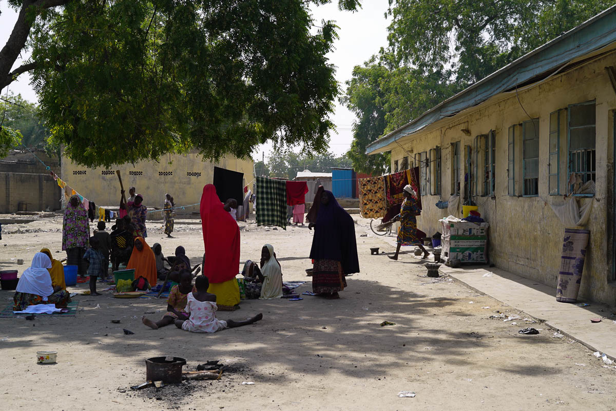 A group of women pass the afternoon in NYSC IDP Camp, which houses around 6,000 Nigerians.  Some are making handicrafts, like the traditional Nigerian caps, in order to make some money to feed their c