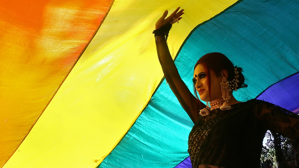 A participant walks under a rainbow flag during a gay pride parade promoting lesbian, gay, bisexual and transgender rights, in Chandigarh, India March 18, 2018 [File: Ajay Verma/Reuters]
