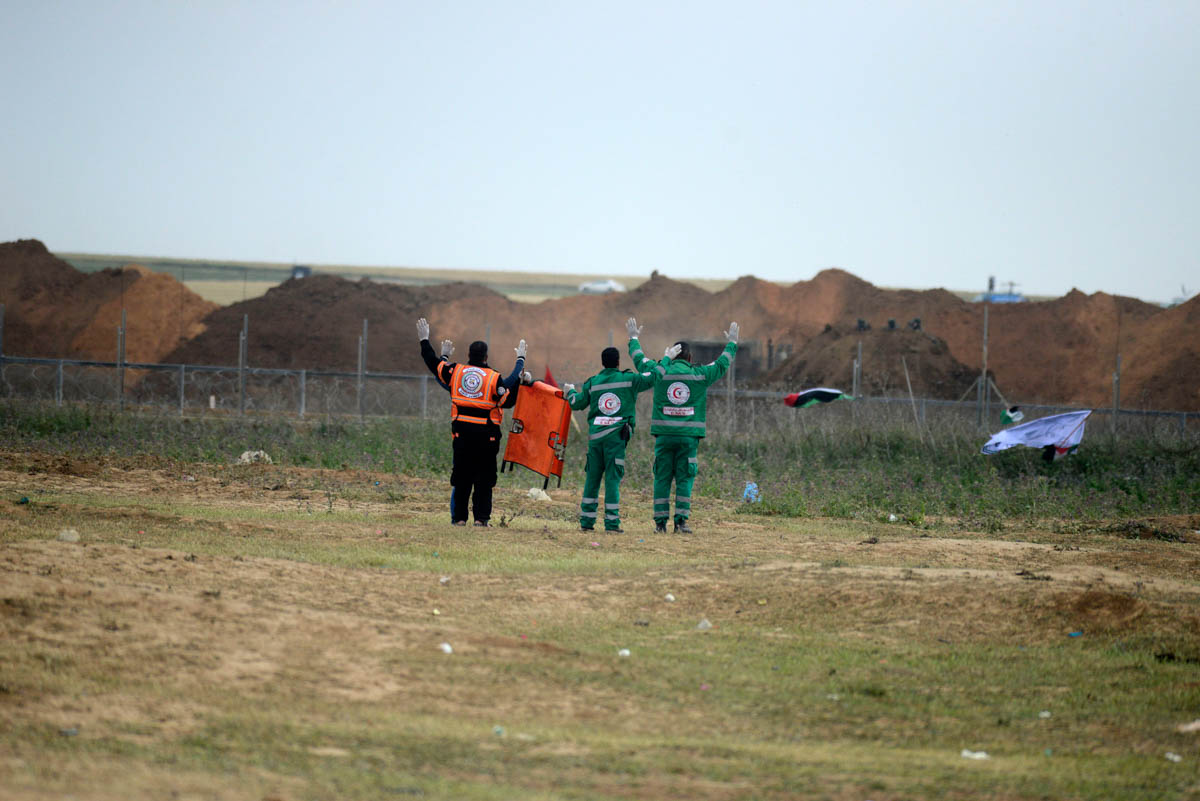 Palestinians medics throw their arms in the air in front of Israeli soldiers in order to reach injured Palestinians during the Land Day demonstration near the Gaza fence in the eastern part of the Gaz