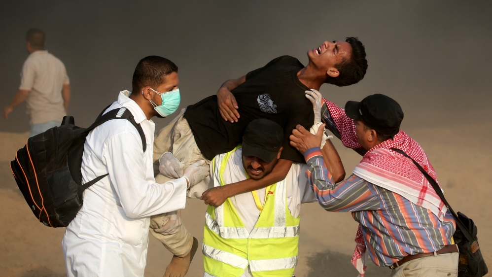 Medics carry a wounded Palestinian man during a protest, demanding Palestinians'' right to return to their homeland, at the fence between Israel and Gaza, in the southern Gaza Strip